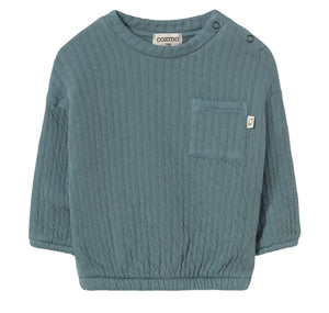The Cozmo Baby Boys’ Chipre Quilted Sweatshirt is a teal, long-sleeve organic cotton sweatshirt featuring a chest pocket with a small brand label, two shoulder snaps for easy changing, and cozy quilted fabric—ideal for comfy fall and winter baby clothes.