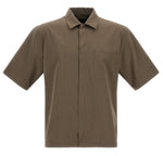 The Herno Seersucker Camp Shirt is a short-sleeved, collared, olive-brown shirt with a single chest pocket and versatile cut, displayed against a white background.