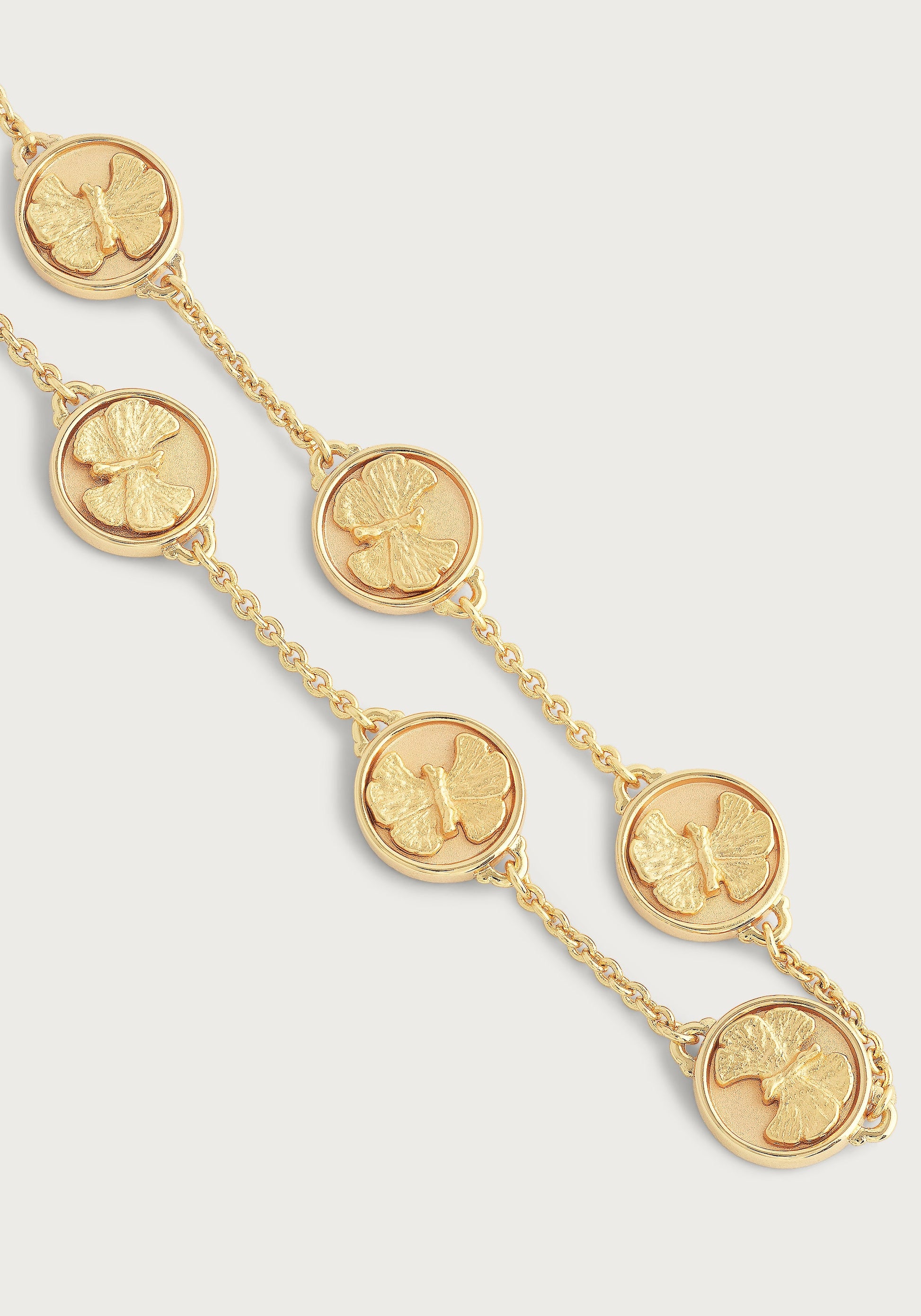 The Anabel Aram Butterfly Coin Charm Bracelet features 18k gold-plated medallions embossed with butterflies. Displayed on a light background, this adjustable bracelet brings elegant charm to any look.