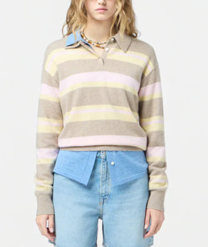 A person wears the Guest in Residence Collegiate Stripe Polo—pink and yellow stripes—over a blue collared shirt and light-wash jeans, standing against a plain background.