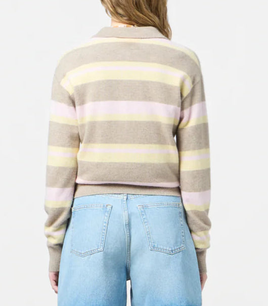 A person wearing the Guest in Residence Collegiate Stripe Polo in beige, pink, and yellow with light blue jeans, shown from the back against a plain background.