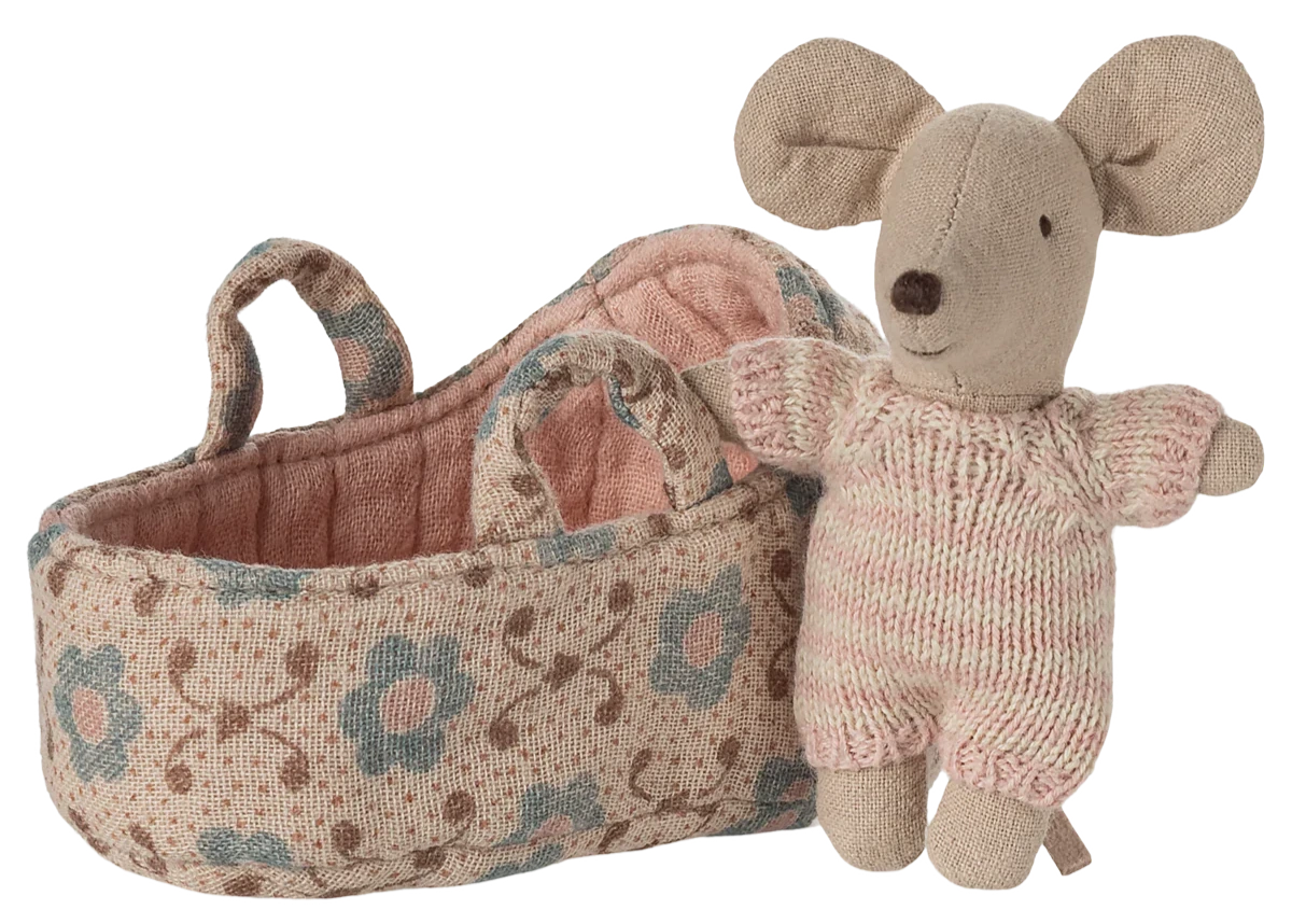 The Maileg Baby Mouse in Carry Cot - Rose features a small mouse in a pink knitted suit, resting beside a floral-patterned fabric carry cot with two handles.