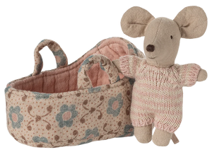 The Maileg Baby Mouse in Carry Cot - Rose features a small mouse in a pink knitted suit, resting beside a floral-patterned fabric carry cot with two handles.