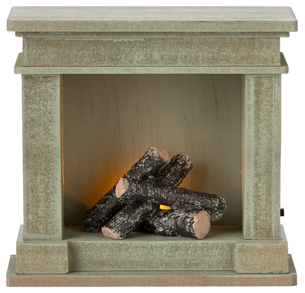 The Maileg Fireplace, Miniature - Dusty Green, features a vintage-style finish with imitation logs and a soft orange light, adding cozy charm to any miniature home.