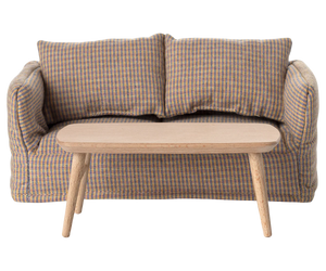 The Maileg Coffee Table, Mouse - Nature is a simple wooden table with four legs, set in front of a small checkered sofa with two cushions—ideal for a mouse-sized space.