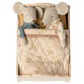 Two Maileg fabric mice dressed in pajamas rest side by side in the Bed, Mouse - Off White, tucked under a patterned quilt for a cozy scene.