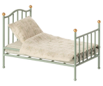 The Maileg Vintage Single Bed, Mouse - Mint features gold-tipped posts and comes with a patterned beige blanket and pillow—a charming, cozy bed for your tiny friends.