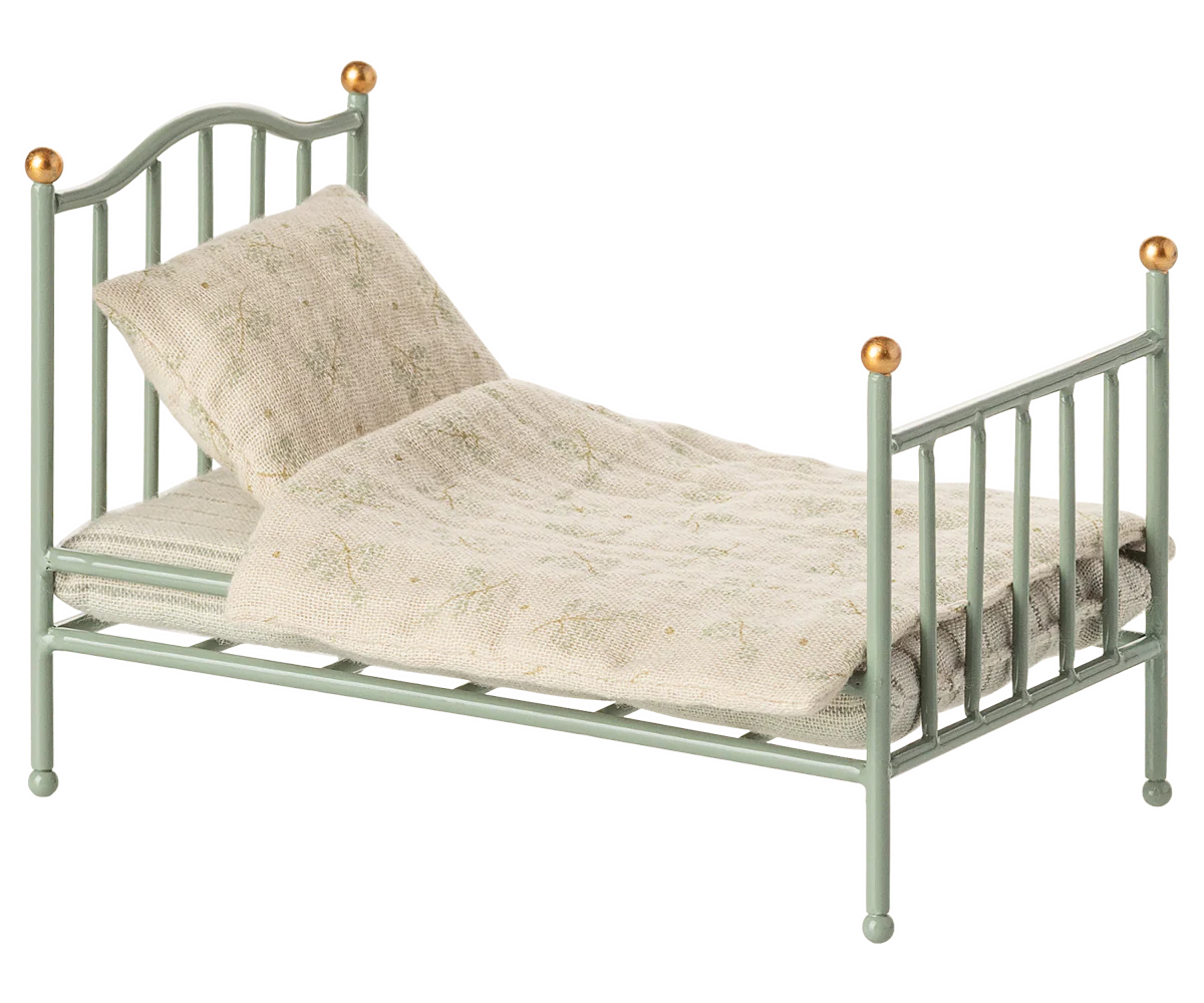 The Maileg Vintage Single Bed, Mouse - Mint features gold-tipped posts and comes with a patterned beige blanket and pillow—a charming, cozy bed for your tiny friends.