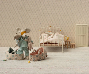 Maileg’s Baby Mouse in Carry Cot - Rose features a charming miniature bedroom scene with a mouse doll, baby mouse, bed, slippers, and nightstand with alarm clock.