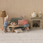Two toy mice in striped shirts are relaxing in their cozy mouse home, complete with a Mouse Sofa Bed, a Maileg Nature Oval Coffee Table – Mouse topped with desserts, a lamp, and a fireplace adorned with a teapot and cups.