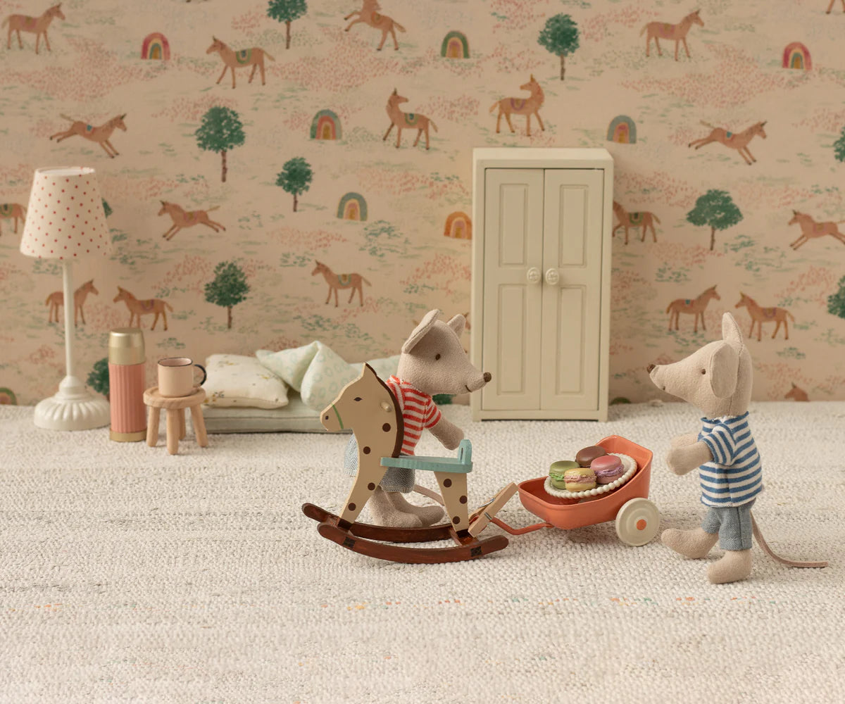 Two toy mice play in a miniature room; one rides a rocker, the other pushes a cart of macarons. The Maileg Vintage Floor Lamp, Mouse - Sand adds soft light, complementing the animal and rainbow wallpaper.