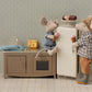 Two toy mice, one sitting and one standing, hold ice cream cones in a miniature kitchen featuring the Maileg Fridge, Mouse - Off White, along with cheese, a fish toy, and a pastry on top—perfect dollhouse accessories for hours of storytelling play.