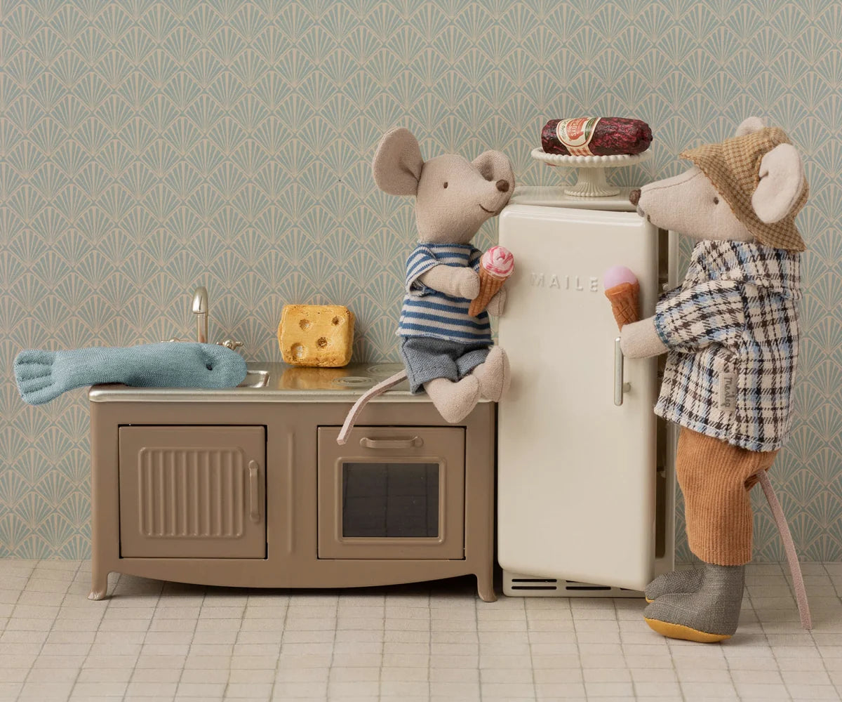 Two toy mice, one sitting and one standing, hold ice cream cones in a miniature kitchen featuring the Maileg Fridge, Mouse - Off White, along with cheese, a fish toy, and a pastry on top—perfect dollhouse accessories for hours of storytelling play.