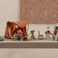 Four small Maileg mouse figurines have set up a delightful camping scene on a table, featuring tents—including the cheerful Happy Camper Tent - Mouse—along with sleeping bags, lanterns, and miniature camping accessories. This whimsical arrangement sparks imaginative play and perfectly captures the joy of outdoor adventures in charming, miniature detail.