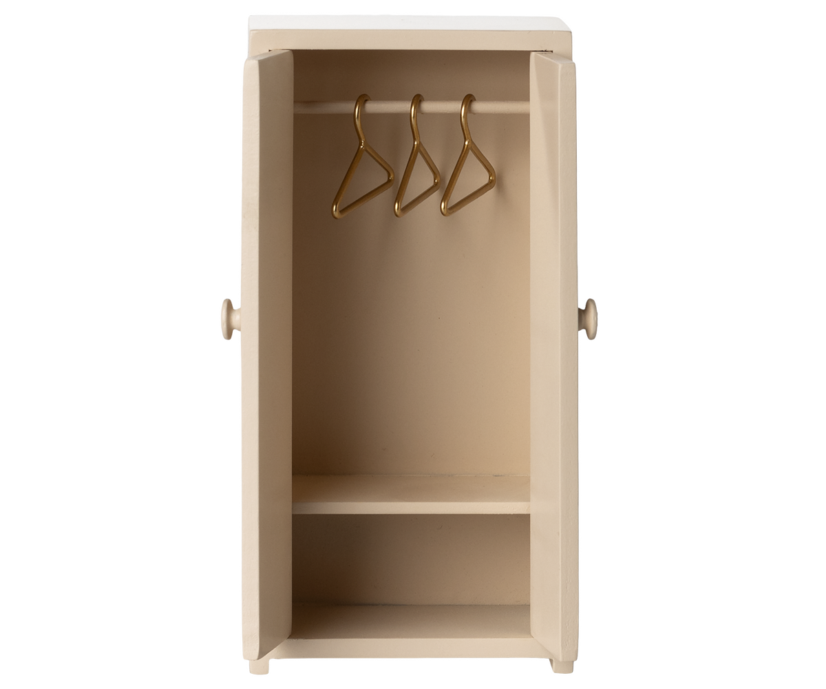 A petite beige wooden "Closet - Mouse" by Maileg features double doors that open to reveal three gold hangers and a bottom shelf—an enchanting addition to any dollhouse or the perfect elegant closet for mice.