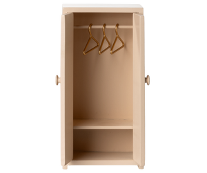 A petite beige wooden "Closet - Mouse" by Maileg features double doors that open to reveal three gold hangers and a bottom shelf—an enchanting addition to any dollhouse or the perfect elegant closet for mice.