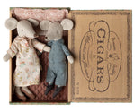 Grandma and Grandpa Mice in Cigarbox by Maileg rest together in their cozy bed, dressed in a floral dress and checked overalls, nestled side by side with a soft pillow and blanket.