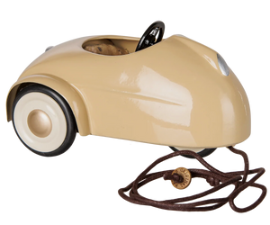 The Maileg Car, Mouse - Wheat is a beige metal car featuring a black steering wheel, white wheels, and a pull string attached to the front—perfect as a pull-along toy or for imaginative play with toy mice, shown against a plain background.