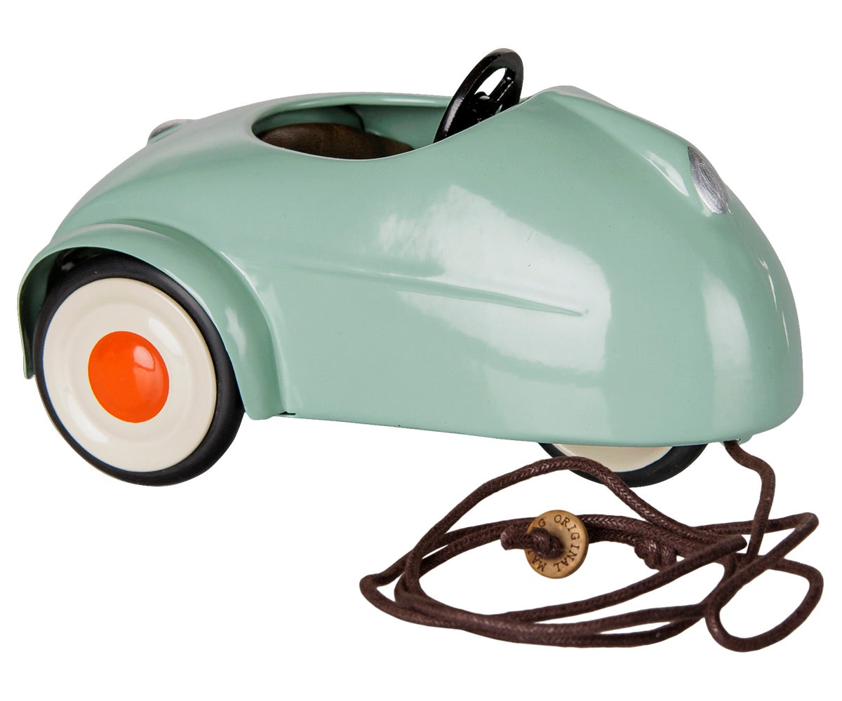 A small Light Mint Car - Mouse by Maileg in mint-green, featuring a red and white wheel, black steering wheel, and a brown pull string with an attached metal tag.