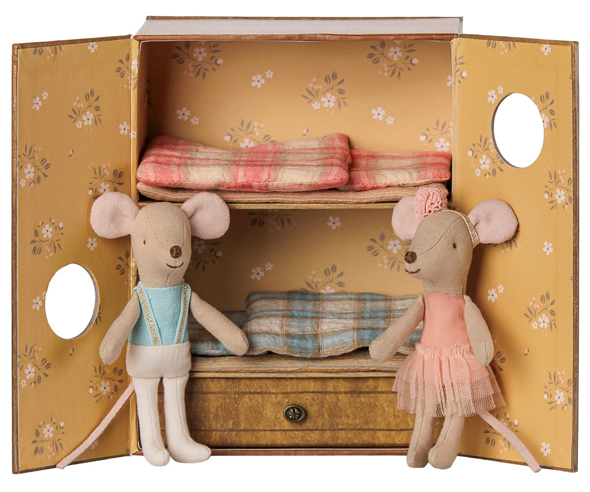 Two Ballet Mice in Dance Studio—Little Sister and Brother by Maileg stand before a yellow wardrobe adorned with floral patterns, revealing two bunk beds with plaid blankets and creating a charming scene in their mouse house.
