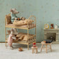 Two Maileg mice with books enjoy a cozy sleepover on the Wheat Bunk Bed - Mouse in a miniature Mouse Hole Farmhouse room, surrounded by a fireplace, clock, cups, and charming small furniture.