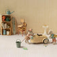 Two Maileg toy mice stand beside a small wheat-colored Car, Mouse in a room furnished with a sink, shelf, chairs, and miniature household items.