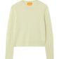 The Compass Shrunken Crew by Guest in Residence is a light yellow women’s slim-fit sweater in a lightweight popcorn stitch, featuring long sleeves with ribbed cuffs and hem, shown laid flat on a white background.