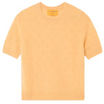 Guest in Residence Compass Sweater Tee: a light orange women's cashmere top with short sleeves, subtle textured pattern, and ribbed collar, cuffs, and hem, shown on a white background.