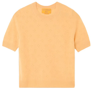 Guest in Residence Compass Sweater Tee: a light orange women's cashmere top with short sleeves, subtle textured pattern, and ribbed collar, cuffs, and hem, shown on a white background.