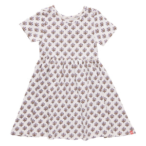 Girls’ Sunny Dress by Coop Kids PC: This versatile dress showcases a white short-sleeve design with a fitted waist and an all-over purple floral pattern, crafted from soft organic Pima cotton, and is displayed on a plain white background.