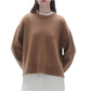 Someone is wearing the Cozy Crew Cashmere Sweater by Guest in Residence, featuring a ribbed neck trim and dropped shoulder design, styled with white pants against a plain background.