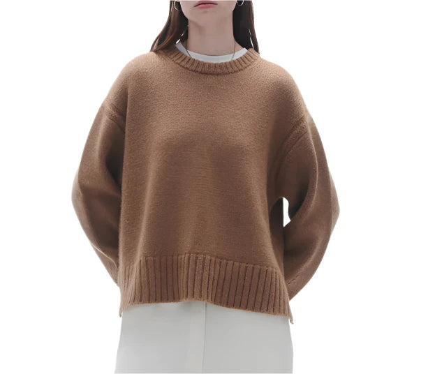 Person wearing a Guest in Residence Cozy Crew Cashmere Sweater, styled with a loose brown look featuring ribbed neck trim over a white garment, standing against a white background.