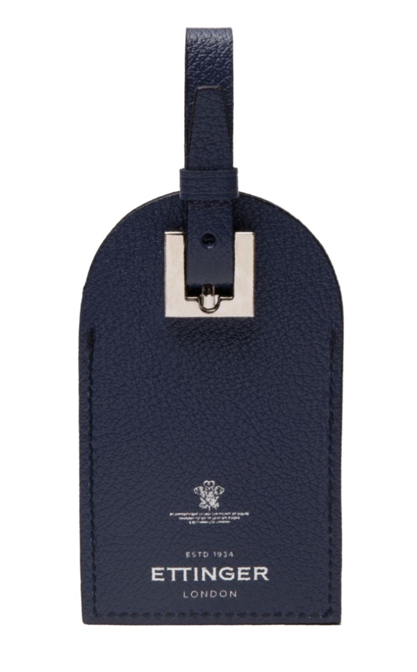 A navy Capra Luggage Tag with Security Flap from Ettinger features goat leather, a silver buckle, embossed "ETTINGER LONDON" and "ESTD 1934" below a small crest.