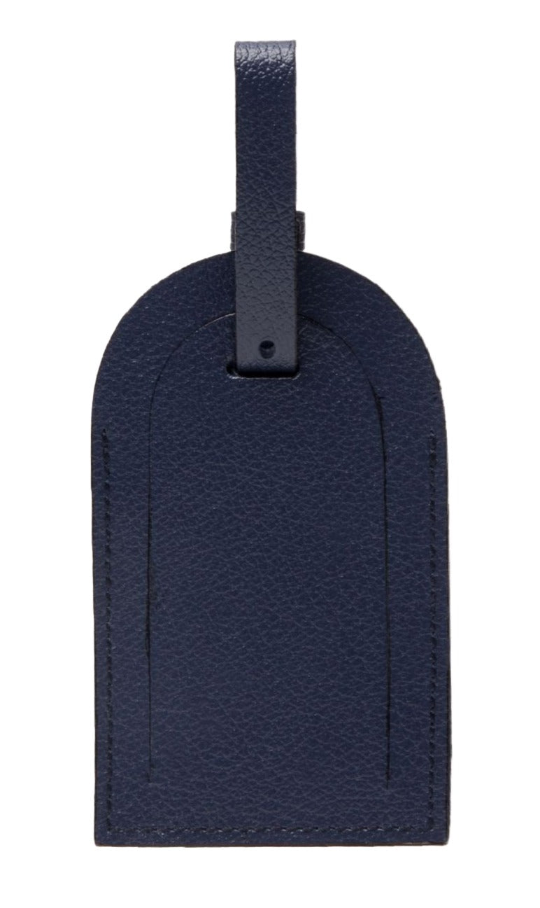 Ettinger's Capra Luggage Tag with Security Flap, from the Capra Collection, is rectangular with a rounded top in dark blue goat leather and includes a strap with a buckle for easy attachment.