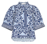 The Cara Cara Calvia Top is a blue and white button-down blouse with geometric and floral prints, a collared neckline, and classic short sleeves—an easy update to your camp shirt collection.