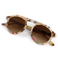 The Krewe Cameron Sunglasses feature round brown lenses and a multicolored speckled acetate frame with a signature brow bar above the nose bridge.