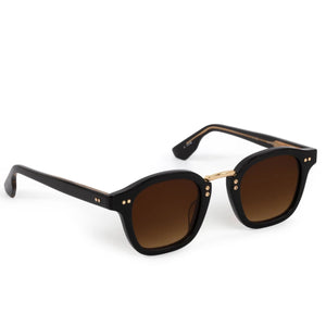 The Campbell Sunglasses by Krewe feature black square frames, brown gradient lenses, and precious metal hinge accents, crafted from hand-made acetate and shown on a white background.