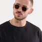 A man with a short beard and buzz cut wears Krewe’s Campbell Polarized Sunglasses and a black crew-neck shirt against a plain light background.