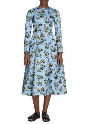 The Genzianella Dress by Emilia Wickstead is a light blue floral print midi with long sleeves and a fitted waist, perfect for special occasions and pairs beautifully with black sandals.