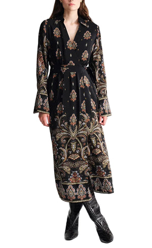 A person wearing the Viv Midi Dress by Cara Cara, featuring long sleeves, a faux wrap style with paisley and floral patterns, V-neckline, and black knee-high boots.