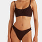 Model is wearing the Hunza G Cassie Bikini in dark brown, featuring a textured finish with a scoop neck top and high-cut bottoms, standing against a plain background.