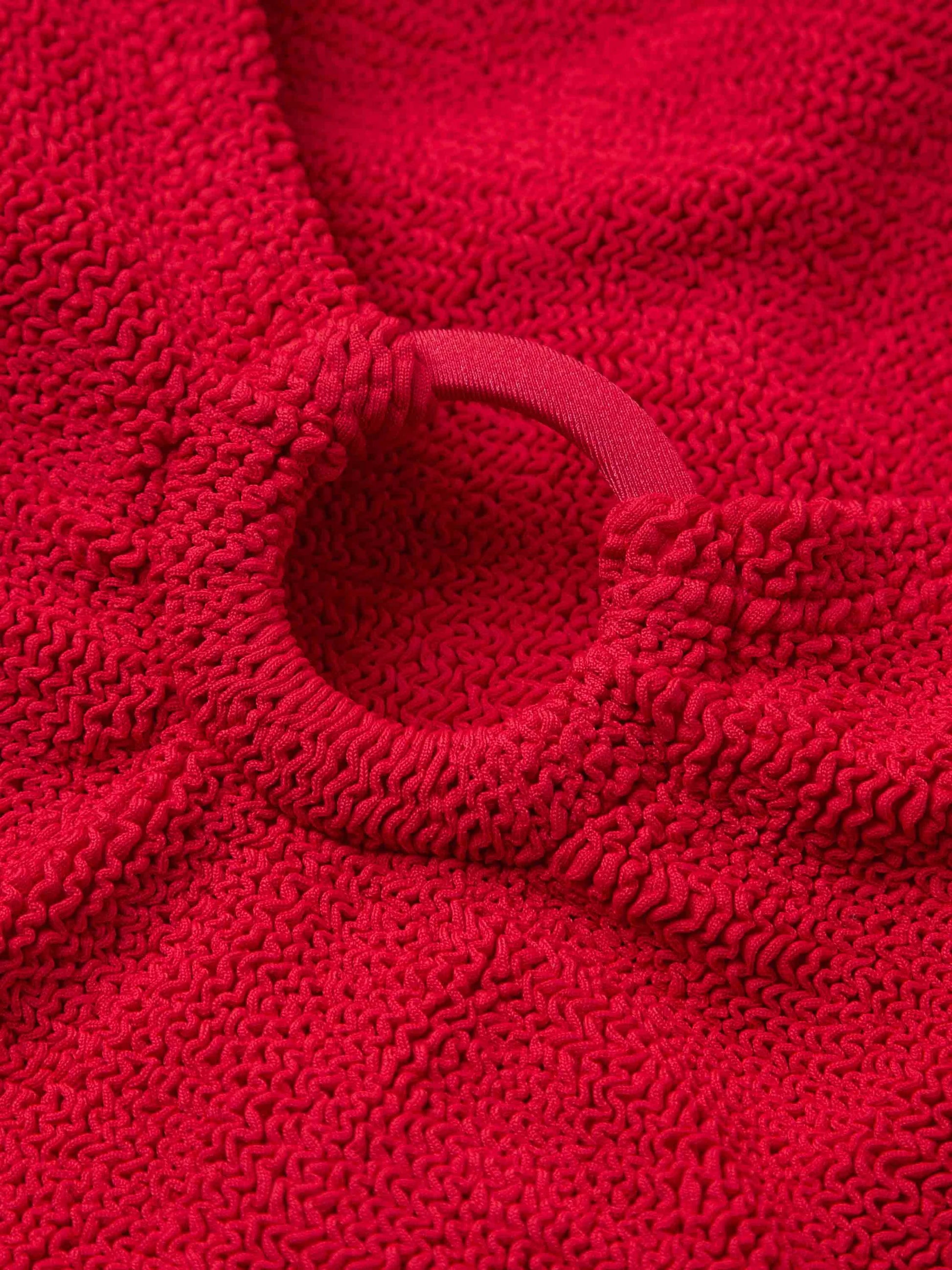 Close-up of the textured red crinkle fabric and elastic hoop detail on the Celine Tonal Hoop Swim by Hunza G, highlighting the signature gathers and ruching found in modern one size swimwear.