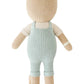 Charlie the Honey Bear by Cuddle + Kind is a 20" knitted teddy in light blue overalls, shown from the back, offering a tender and loving companion perfect for any family.