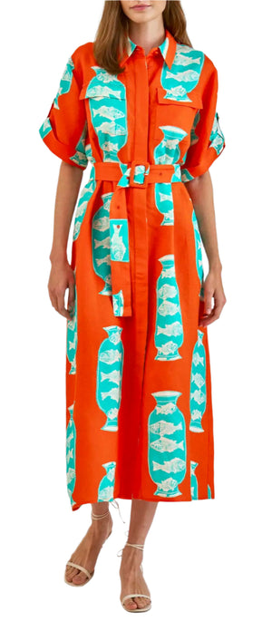 A woman wears the Hunter Bell NYC Charlotte Dress, a bright orange oversized fit with teal and white vase print, short sleeves, collar, button-down front, paired with strappy sandals.