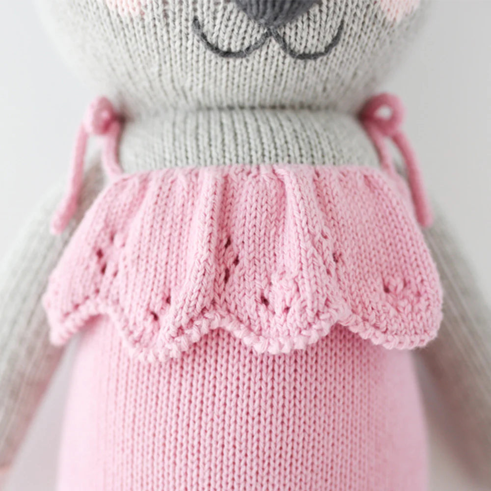 Close-up of Claire the Koala by Cuddle + Kind, a 20" knitted stuffed animal in a pink dress with scalloped edges and delicate patterns, ready for magical adventures with BFFs in their cozy treehouse.
