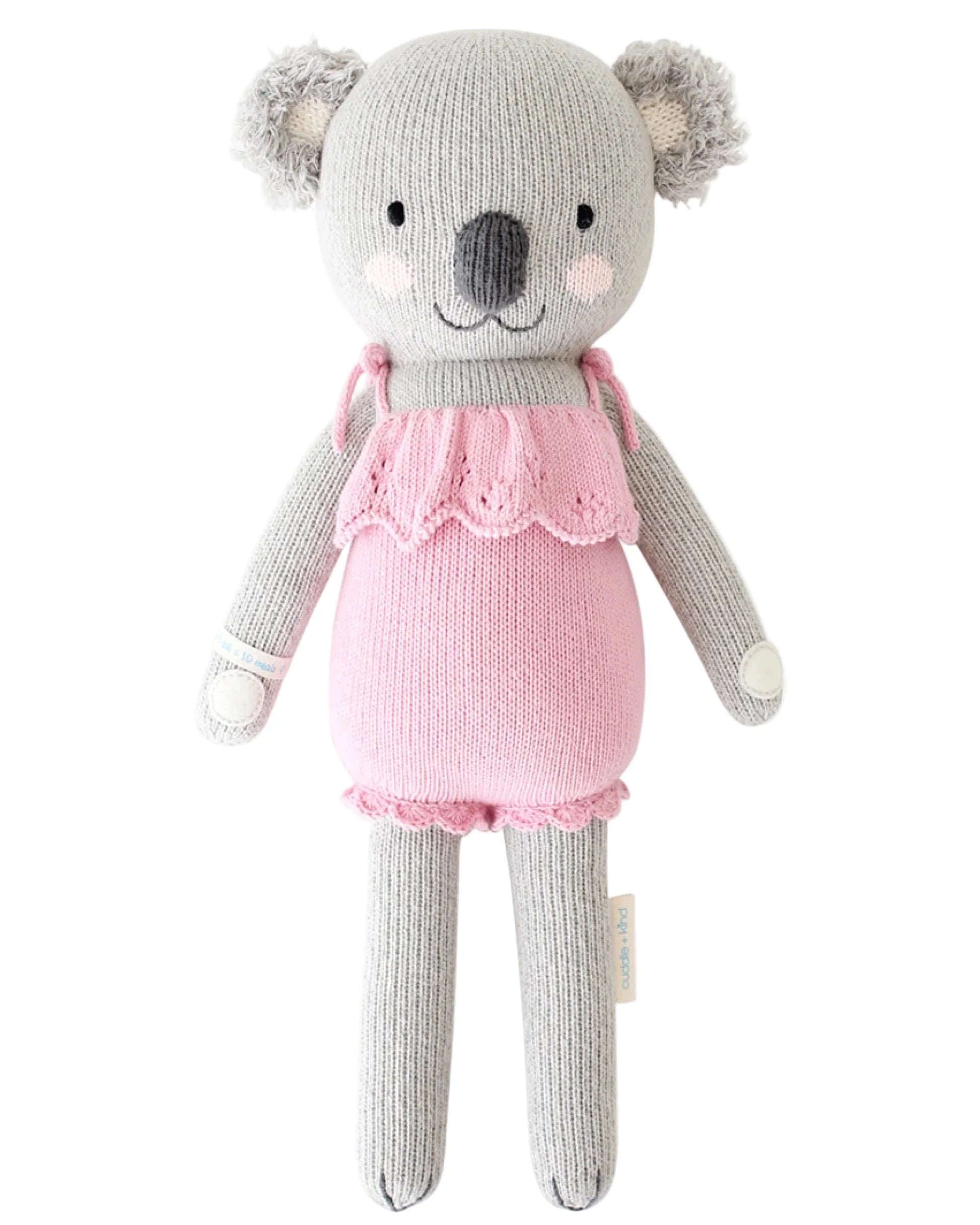 Claire the Koala – Regular 20" by Cuddle + Kind is a gray knit plush wearing a light pink ruffle dress, perfect for imaginative play. Shown against a white background.