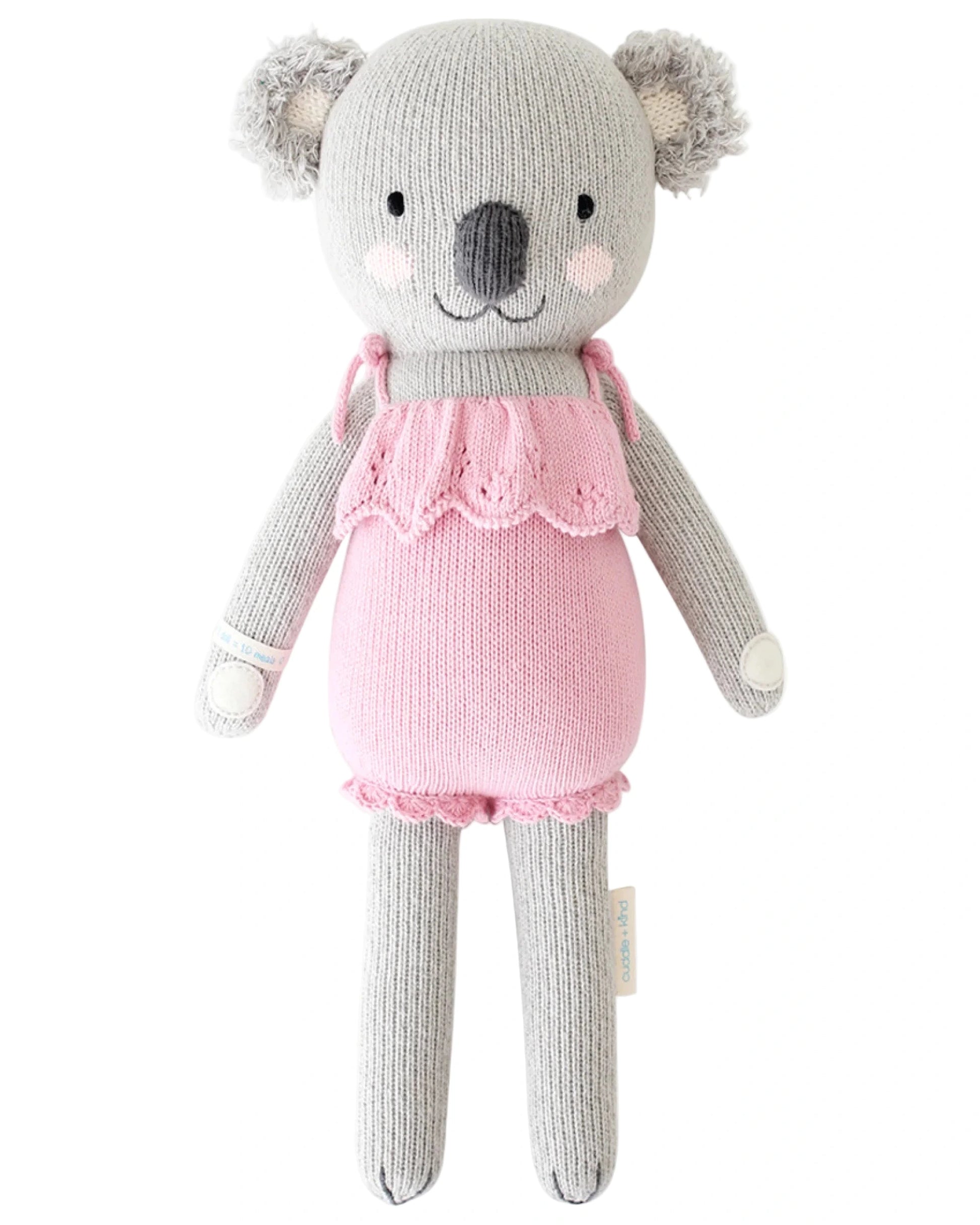 Claire the Koala - Little 13" by Cuddle + Kind is a knitted gray plush toy in a pink ruffled dress, posed upright against a white background—an adorable friend for magical adventures or birthday cuddles on December 3rd.