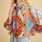 Wearing the Hunter Bell NYC Clarke Shirt, featuring a modern boxy fit and colorful patterns with wide sleeves, paired with light denim jeans, a person stands against a beige background.