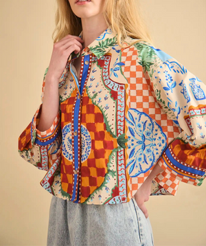Wearing the Hunter Bell NYC Clarke Shirt, featuring a modern boxy fit and colorful patterns with wide sleeves, paired with light denim jeans, a person stands against a beige background.