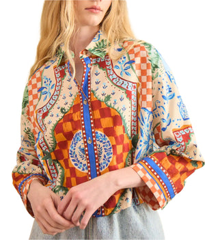 A person wearing the Clarke Shirt by Hunter Bell NYC, featuring a modern boxy fit with colorful, intricate checks, floral, and geometric designs, paired with light blue jeans.